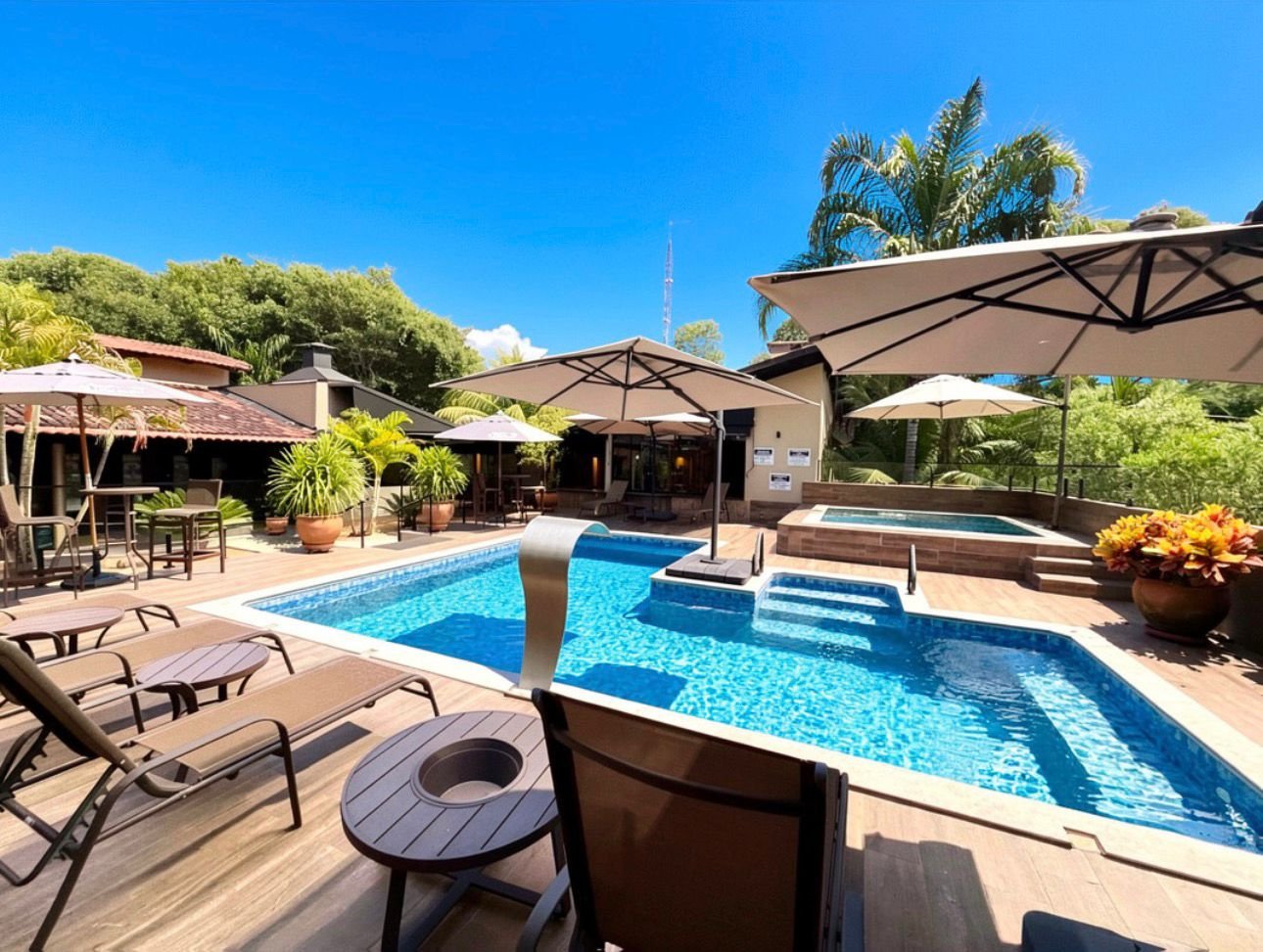 Deck da piscina com espreguiçadeiras e ombrelones